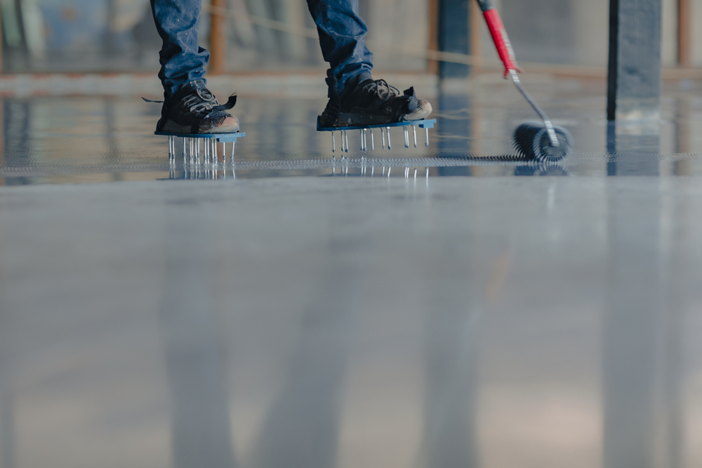 worker applying gray epoxy on floor